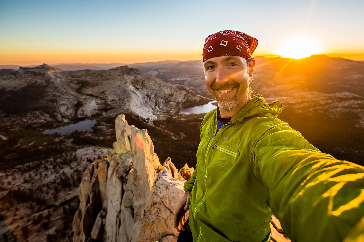 Smiling mountain man on summit of Cathedral Peak out of Tuolumne Meadows in Yosemite National Park.