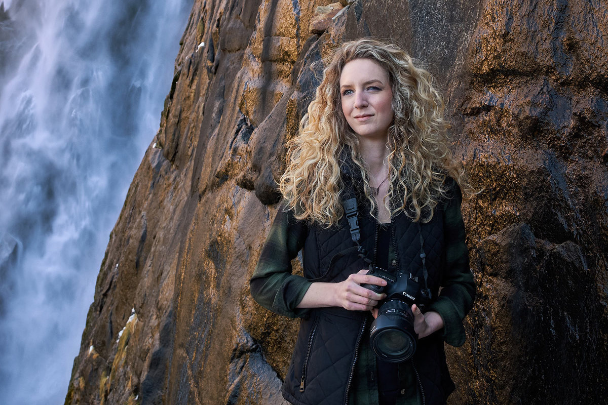 Brittany Colt and camera in front of waterfall in Yosemite.