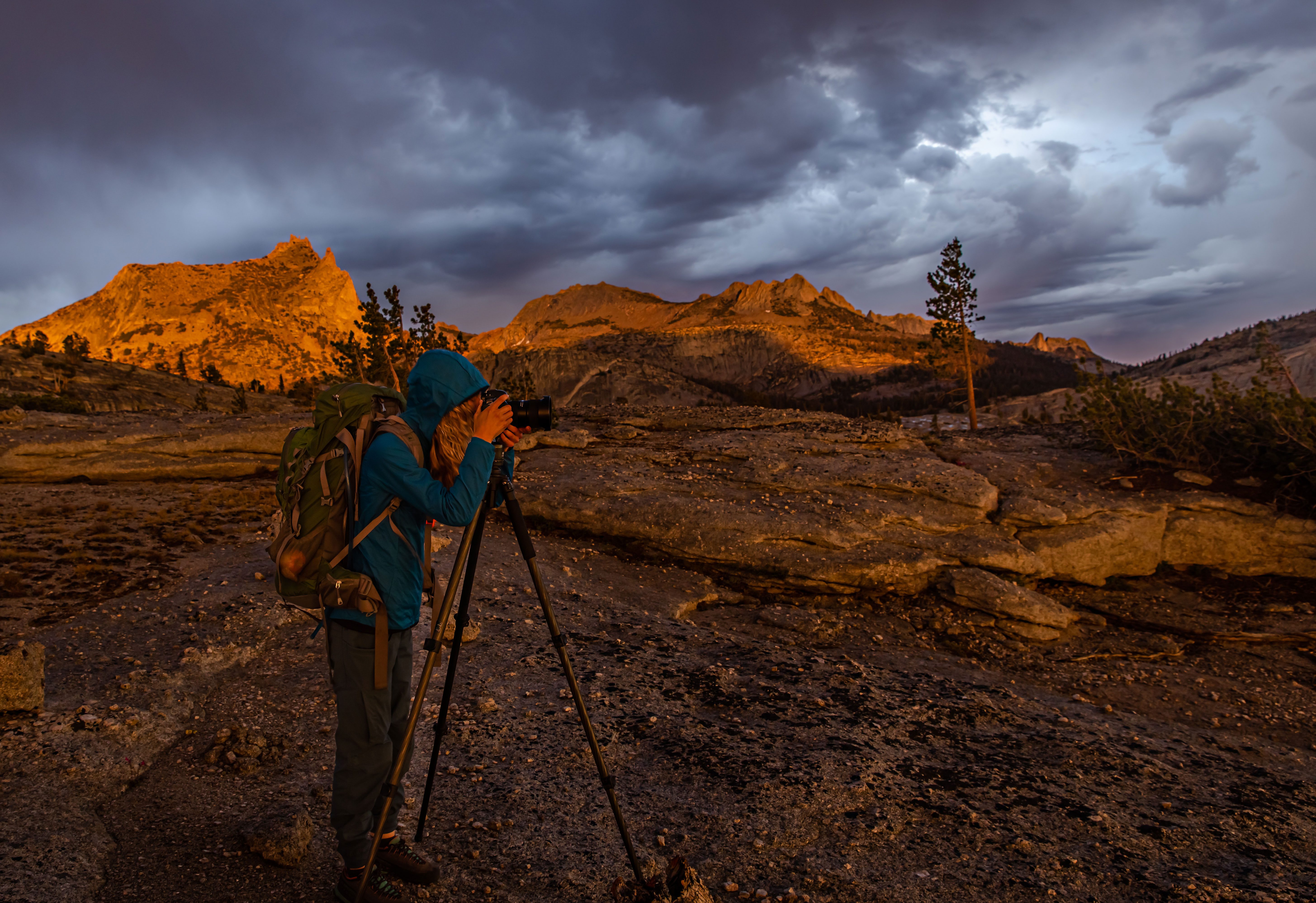 Young woman photographer photographing stormy sunset in Yosemite's backcountry.
