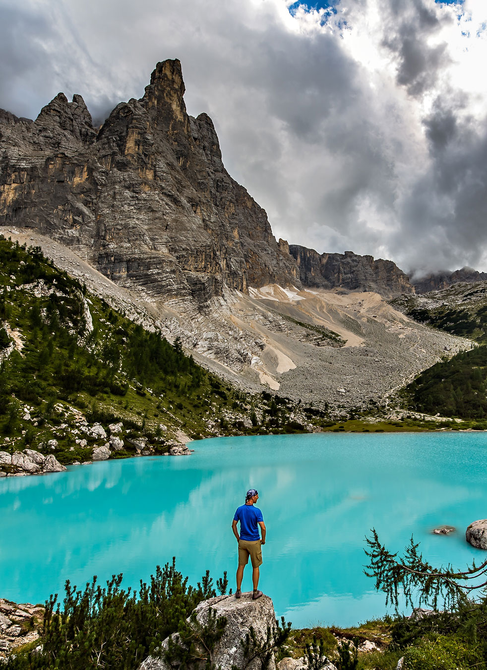 Man standing over turquoise backcountry lake in the Dolomites of Italy.